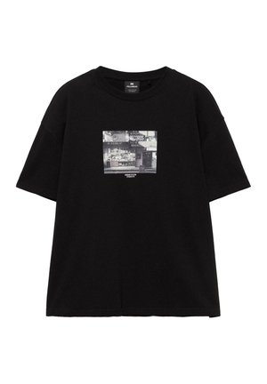 Čierne tričko s krátkym rukávom s grafickým zobrazením predajne s platňami v odtieňoch sivej a textom „Urban Vision Studio 91" na hrudi.