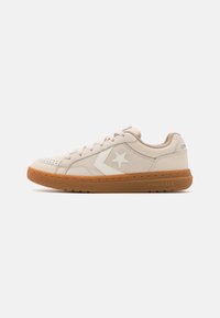 Beige szövetből készült sneaker, fehér csillaglogóval és világosbarna gumitalppal. Perforációkkal és kontrasztos varrással rendelkezik.
