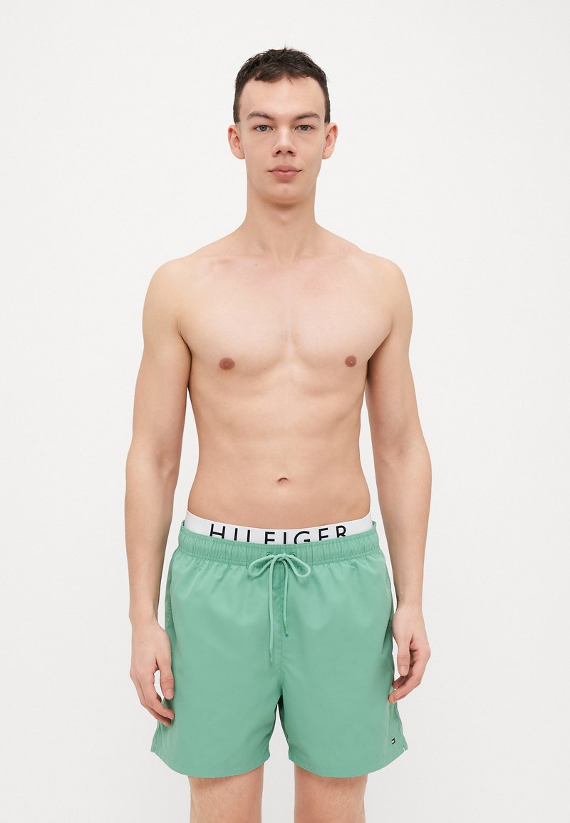 Shorts de bain verts en matériau léger, dotés d'une taille élastique avec cordon de serrage et de détails de logo en noir.