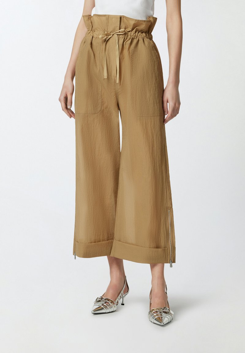 Kakhi široke hlače s teksturiranom završnom obradom, elastičnim pojasom, zatvaranjem na vezicu i bočnom zip zatvaranjem. Uparen s srebrnim potpeticama.