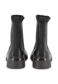 Bottines en simili cuir noir pour enfants, avec des panneaux élastiques sur les côtés, des accents côtelés et des semelles de plateforme brillantes contrastantes.