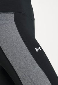 Svarta och grå träningsleggings med en slät yta, en åtsittande design och en Under Armour-logotyp på underbenet.