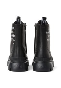 Čierne kožené členkové topánky so striebornými zipsami, masívnymi podrážkami a bielym textom na vonkajších stranách. Obsahujú logo na päte.