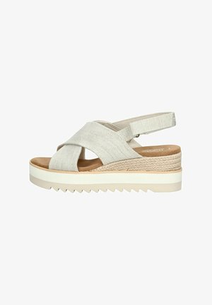 Sandal con incrocio beige realizzato in tessuto testurizzato. Presenta una soletta imbottita e una piattaforma con un accento in juta intrecciata e suola seghettata.