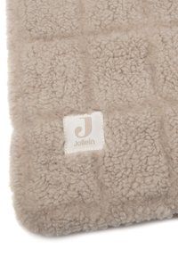 Beige textuurde deken met een gewatteerd patroon en een wit stoffen label met de merknaam "Jollein."