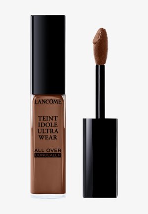 Il correttore Lancôme Teint Idole Ultra Wear in un tubetto marrone, con un tappo nero. Include un applicatore a forma di piede di cervo con punta in spugna testurizzata.