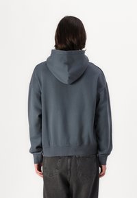 Dunkelgrauer Hoodie mit einer großen Kapuze, überschnittenen Schultern und gerippten Bündchen sowie Saum. Verfügt über eine glatte Textur und ein lässiges Design.