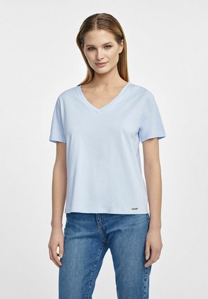 Jasnoniebieska koszulka typu v-neck z krótkim rękawem, wykonana z miękkiego materiału, z luźnym krojem i małym logo na dole.