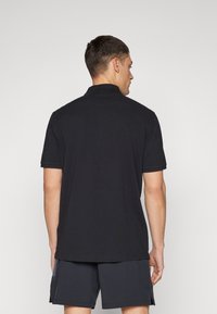 Schwarz Poloshirt mit strukturiertem Kragen und kurzen Ärmeln, hergestellt aus leichtem Stoff. Das Design hat einen geraden Saum und einen schlichten Schnitt.