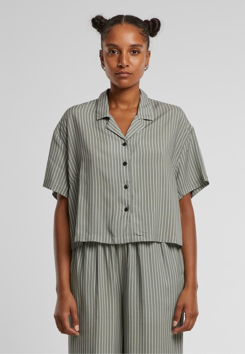 Cropped button-up shirt in olive green with white vertical stripes, short sleeves, and a relaxed fit; made of soft, smooth fabric.