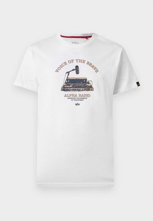 Camiseta blanca con gráfico de radio vintage y micrófono, texto "Voz de los Valientes" y "Alpha Radio Llevando la Misión a la Calle."