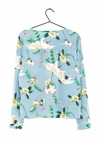 Blouse à manches longues en tissu bleu clair avec un imprimé floral et de grues. Il présente un col rond et une coupe décontractée.
