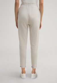 Helle beige Jogginghosen mit lockerer Passform, elastischem Bund und umgeschlagenen Säumen. Aus weichem Stoff gefertigt, geeignet für Freizeitkleidung.