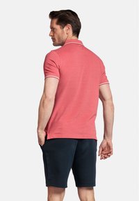 Rode polo shirt met een kraag, korte mouwen en witte accentstrepen bij de manchetten, gecombineerd met marineblauwe shorts. Glad stofgevoel.