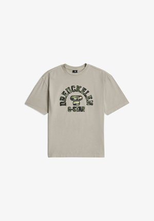Beżowy T-shirt z krótkim rękawem i okrągłym dekoltem, z tekstem "BREUCKELEN" i "G-STAR" w nadruku moro na przodzie.