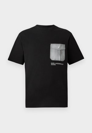 Juodas medvilninis marškinėliai trumpomis rankovėmis, su dideliu pilku kišeniu kairėje krūtinės pusėje ir baltais užrašais "KARL LAGERFELD JEANS."