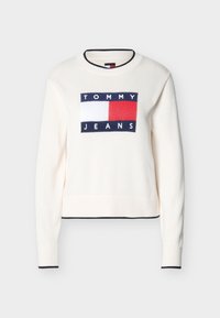 Pull blanc à col rond avec bordure bleu marine, présentant un logo rectangulaire Tommy Jeans en bleu marine, blanc et rouge centré sur la poitrine.
