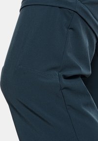 Ciemnoniebieskie, lekkie spodnie damskie o gładkiej teksturze, z dopasowanym krojem, subtelnymi detalami stębnowania i średnim stanem.