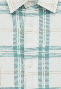 Chemise à boutons avec un motif à carreaux blanc et bleu sarcelle clair. Fabriquée en tissu doux, elle présente des boutons blancs et un col classique.