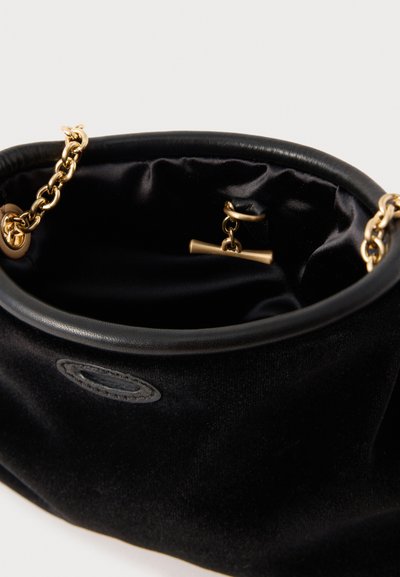 Mala de veludo preta com interior em cetim, detalhes em corrente dourada, borda de couro suave e um pequeno detalhe decorativo em metal no interior.