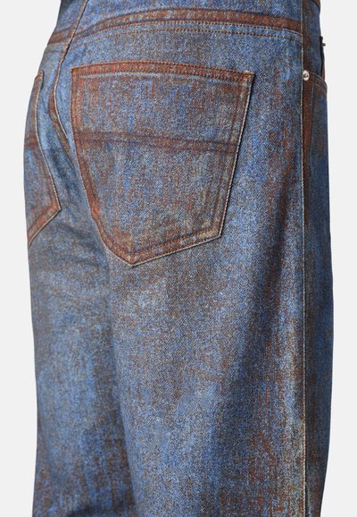 Jeans in denim blu con una superficie testurizzata. Presentano una tasca posteriore con cuciture a contrasto e un sottile motivo invecchiato.