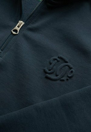 Marine blauwe zip-up sweater gemaakt van gestructureerde stof, met een subtiel reliëflogo op de linkerborst en een metalen rits.