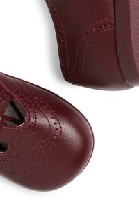 Burgundské kožené boty s vykrojenými okraji, vybavené otevřenými šněrovacími otvory a kontrastním prošíváním. Hladký povrch a kulatý design špičky.