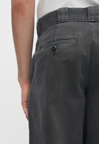Szare bawełniane spodnie z prostym krojem, zdobione tylną kieszenią z czarnym guzikem i teksturowanym materiałem.