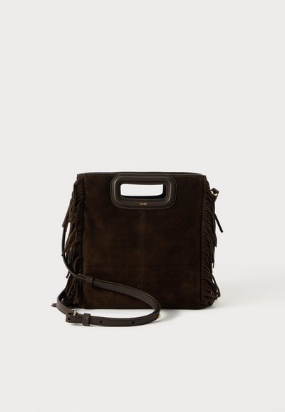 Dark brown suede handbag with fringe sides, rectangular cut-out handle, and adjustable leather shoulder strap against white background.