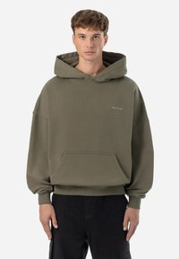 Felpa khaki realizzata in morbido tessuto, dotata di una grande tasca frontale, polsini a coste e cappuccio con cordino, con un piccolo logo ricamato sul petto.