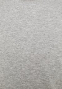 Maglione grigio chiaro a girocollo realizzato in un tessuto morbido e testurizzato con un leggero motivo melange. Presenta un dettaglio a V nella scollatura.