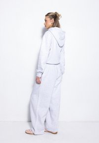 Jasnoszary, wygodny zestaw z kapturem i szerokimi spodniami. Miękka tkanina, kieszeń kangurza i regulowany kaptur. Luźny krój z subtelnymi detalami przeszycia.