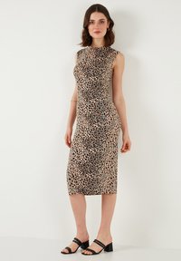 Leopard print fitted dress with a round neck, sleeveless design, and knee-length hem. Smooth fabric and subtle sheen. Black strappy sandals.