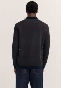 Dunkelgrauer Strickpullover mit einer gerippten Textur und einem kontrastierenden blauen Kragen und Bündchen. Verfügt über ein gerades Design und lange Ärmel.