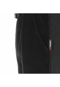 Tejido de forro polar negro con una textura suave, que presenta un bolsillo lateral y una etiqueta de logo visible. El diseño incluye un corte simple y funcional.