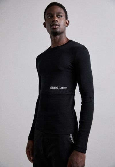 Must mustärg paigaldi varrukatega särk, millel on ribakujuline tekstuur, omab vormitud disaini ja valge "Moschino Couture" bränding rindkere piirkonnas.