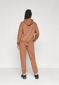 Brown hoodie and matching sweatpants made of soft fabric, featuring a relaxed fit, elastic cuffs, and a drawstring hood.