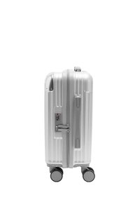 Srebrna walizka z twardą skorupą o żebrowanej fakturze, zamykana na suwak, wyposażona w zamek szyfrowy i cztery kółka ułatwiające przemieszczanie.