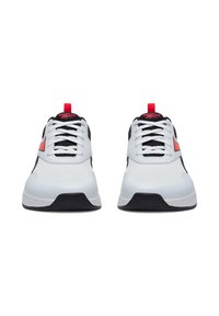 Białe buty sportowe z czarnymi akcentami i czerwonymi detalami, z teksturowaną cholewką, sznurowaniem oraz kontrastową czarną podeszwą.