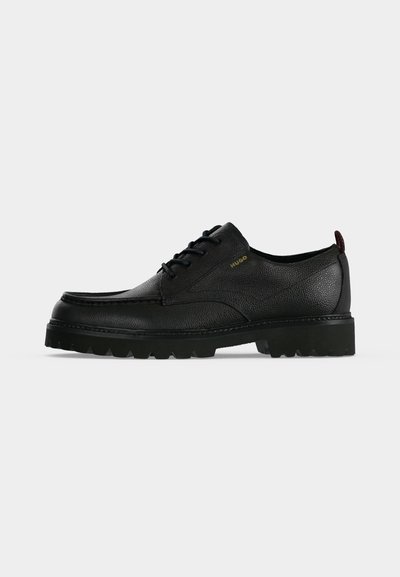 Chaussure à lacets en cuir noir texturé avec semelle épaisse en caoutchouc et logo "HUGO" sur le côté, vue du côté extérieur.