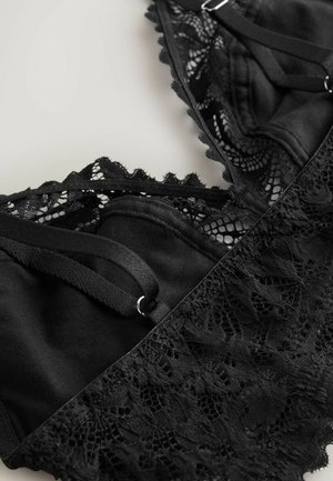 Black lace bralette featuring intricate floral patterns, adjustable straps, and a smooth fabric base with a scalloped edge detail.