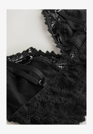 Black lace bralette featuring intricate floral patterns, adjustable straps, and a smooth fabric base with a scalloped edge detail.