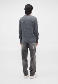 Pulover gri, tricotat, cu guler rotund, manșete și tiv cu nervuri, asortat cu blugi gri pal și adidași albi. Textura pare moale.