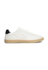 Λευκό sneaker χαμηλού ύψους με μπεζ σόλα, μαύρο σημείο στη φτέρνα, υφασμένο πλαϊνό πάνελ και χρυσό λογότυπο "Hilfiger" κοντά στη φτέρνα.