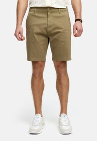 Khaki-shortsit on valmistettu puuvillasekoitteesta, ja niissä on klassinen design, litteä etuosa ja sivutaskut. Yhdistetty valkoisiin urheilujalkineisiin.