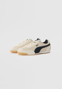 Sneakers din suede bej cu un accent din suede negru, având o talpă din cauciuc și un design texturat. Vin cu șireturi și un guler căptușit.