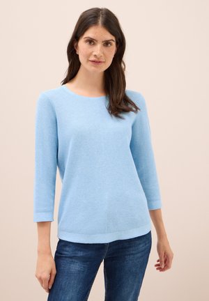 Pull en tricot bleu clair avec un col rond et des manches trois-quarts. Texture douce, coupe décontractée, associé à un jean bleu foncé.