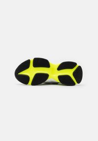 Suela de zapato con un patrón de banda de rodadura de goma negra y una entresuela amarilla brillante. Bordes suaves y una ligera curvatura para ofrecer soporte.