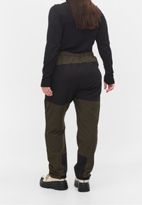 Černý pletený top se zeleným elastickým pasem a kalhotami ve stylu cargo v černé a olivové barvě. Texturovaná látka, tapered střih a boty s robustní podrážkou.