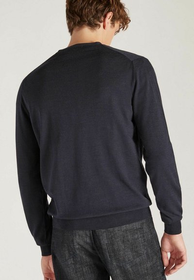 Pull-over en maille bleu marine à manches longues avec une texture lisse, col rond et poignets côtelés ; associé à un pantalon gris texturé.